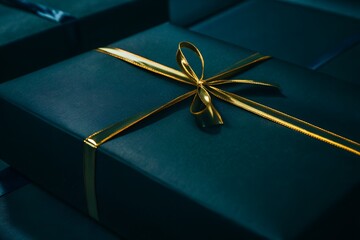 Closeup of a dark teal gift box with a shiny golden ribbon, perfect for celebrations