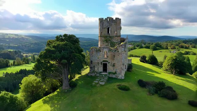 Medieval stone tower on green hill overlooking countryside, dramatic clouds and rolling fields below
