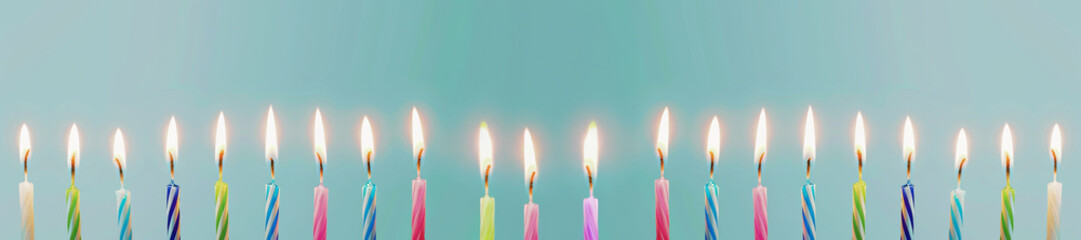 Set of colored birthday candles in a row on light pastel blue background. Celebration birthday cake colorful birthday candles