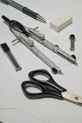 compass and scissors on white sheet of paper