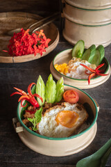 Beautifully presented stir-fried pork with basil and a fried egg, served in a vintage style plate garnished with fresh chilies, cucumber and herbs, this simple.