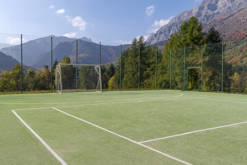 Football field with forest and mountain in back, Alps, Italy