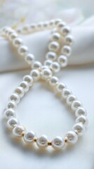 Close-up of a double-stranded pearl necklace resting on a silky white fabric