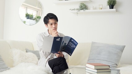 投資について考えるアジア人男性 © mapo