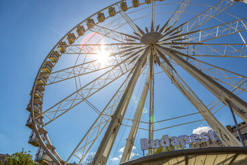 Ferris wheel in Budapest, Hungary, modern city attraction with sunlight and blue sky viewed from below