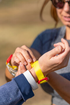 Close-up of a woman placing a yellow chip registration bracelet on an athlete's arm before an obstacle course or event.