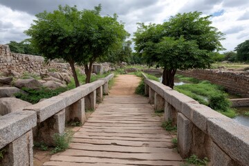 Fototapeta premium Stone bridge spans a waterway framed by trees and weathered stone walls under a cloudy sky