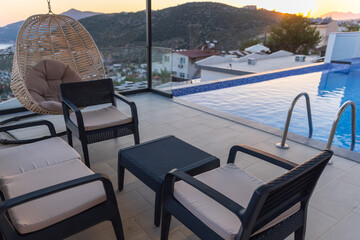 A relaxing rooftop poolside lounge with cushioned seating and hanging chair
