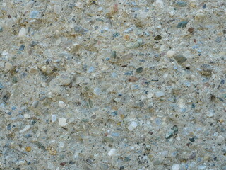 Uneven concrete wall with embedded pebbles. Close-up. Copyspace.