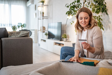 Woman booking travel using tablet and credit card at home