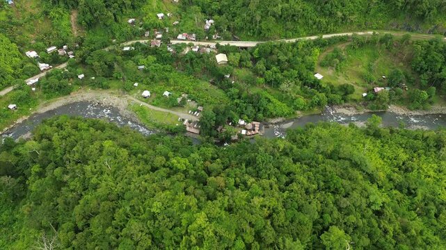 High drone shot glides over forested hills, then descends to Tampisaw River & Eco Park on an emerald river with rapids and natural pools in Napsan, Puerto Princesa, Palawan, Philippines.