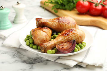 Grilled chicken drumsticks served with green peas on white marble table, closeup