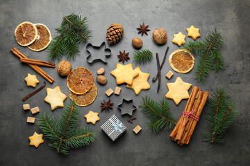 Christmas composition with fir tree branches, cookies, cutters and spices on grey table, flat lay