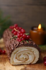 Delicious Yule log (traditional Christmas cake) with redcurrant on table, closeup