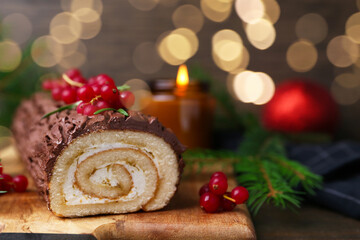 Delicious Yule log (traditional Christmas cake) with redcurrant on table, closeup. Space for text