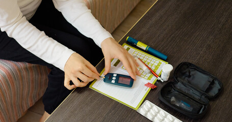 A woman carefully inserts a test strip into a glucometer to monitor her blood sugar levels. This routine check helps track her diabetes management effectively.