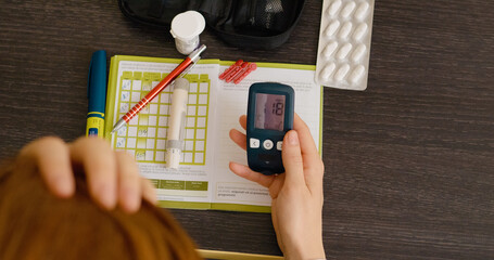A woman examines her glucometer, which shows a high blood sugar reading. She is actively monitoring her health as part of her diabetes management routine.