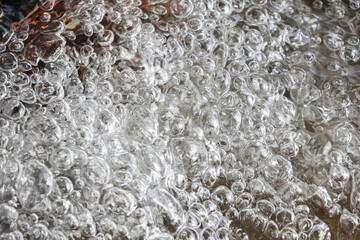 Close up of energetic clear boiling water with many bubbles creating an abstract background texture. hot liquid surface showing dynamic movement and effervescence