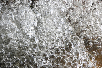 Naklejka premium Close up view of clear boiling water with many bubbles. An energetic and dynamic liquid background showing vibrant texture of pure water and steam in active motion