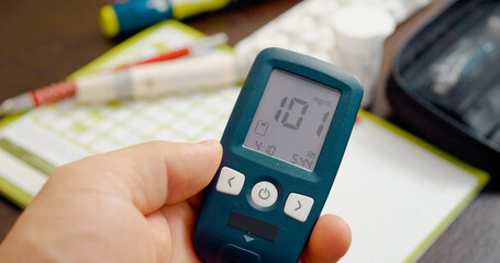 A person tests their blood sugar using a glucometer at home. The result indicates slightly elevated glucose levels, suggesting prediabetes. Monitoring is essential for health.