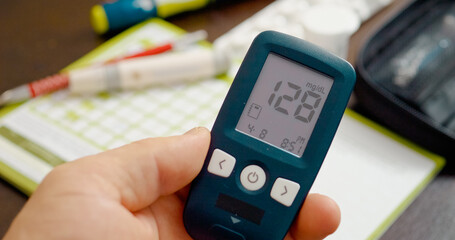 A person checks their glucometer, revealing an elevated blood sugar level. This highlights the ongoing challenge of diabetes management and monitoring health.