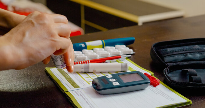 A woman prepares to monitor her blood sugar levels by inserting a test strip into a glucometer at home. This helps in managing her diabetes effectively.