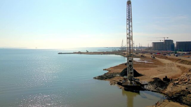 Large crawler crane working at a construction site by the sea, hyper-lapse video.