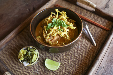 Delicious Khao Soi, savory Thai food featuring northern noodle curry soup. This traditional Asian cuisine in bowl with lime and pickle offers an appetizing and comforting meal