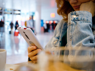 Woman hands answering messages on smartphone in the airport sitting at table. Female waiting in the...