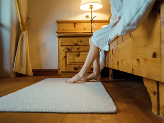 Low angle of a young caucasian woman's legs going down from the bed to the floor. A girl in...