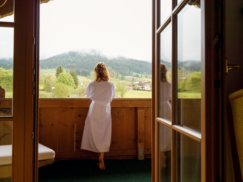 Back view of tourist female enjoying the mountain view from her room. Paradise vacation relaxation with beautiful overview to the mounts.