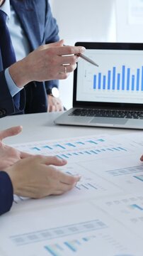 Businessman discussing financial data, market trends with colleagues while sitting at the table with financial charts during a corporate meeting in office. Business people concept