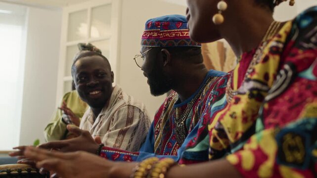 Happy company of Black young people playing goblet drums and smiling during week-long celebration of African heritage