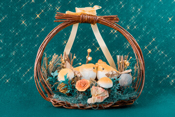 Charming decorative basket with two cute bird figurines, faux mushrooms, flowers, and natural elements on a teal, sparkling background. Perfect for seasonal decor or a thoughtful gift.