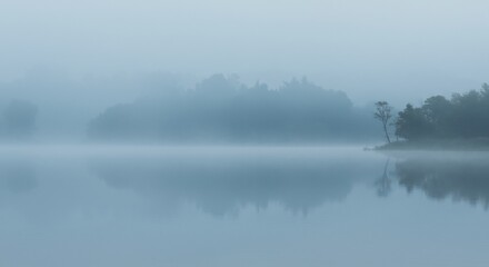 Obraz premium Misty lake scene trees mirrored in still water veiled by fog