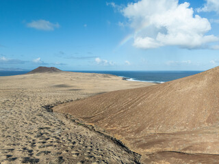 Aerial view of volcanic cones and arid landscape on La Graciosa Island, Canary Islands, with distant views of surrounding islands and the Atlantic Ocean.
