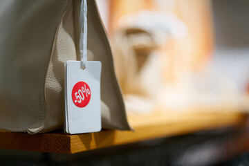 Schild mit der Aufschrift -50% an einer Handtasche als Hinweis auf ein Sonderangebot zum halben...