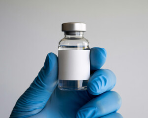 Cautious hand in blue glove holds clear vial with blank label, ready for medical research or pharmaceutical development