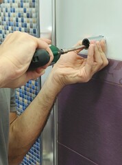 Man drilling a hole in the tile of bathroom