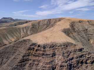 Aerial view of volcanic cones and arid terrain on La Graciosa Island near Lanzarote, with the Atlantic Ocean in the background.
