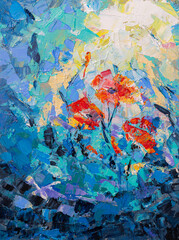 Red poppies growing in a field with blue and purple flowers