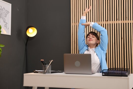 Young businesswoman stretching her arm at table in office