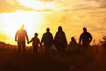Fototapeta premium Family holding hands in field at sunset