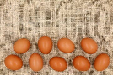 Fresh chicken eggs in top view on a burlap background. Easter concept with copy space.