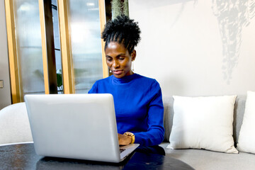 Serious African businesswoman with curly hair works and types on laptop computer. Business female...