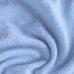 Blue cashmere fabric, textile is folded, knitwear texture, natural fabric, top view. Soft light blue fabric texture with soft folds.