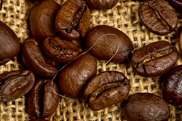 Macro close-up showing detailed roasted coffee beans on a burlap background. Perfect for use in cafe branding, coffee packaging, or warm rustic food visuals.