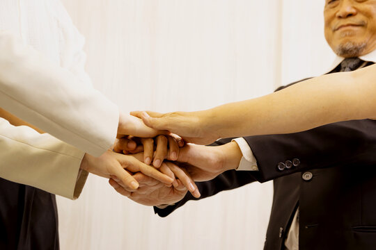Three businesspeople join hands together. Group of diverse business worker joining hands to show unity and harmony. Partnership colleagues team hold hands as commitment of strong support teamwork.