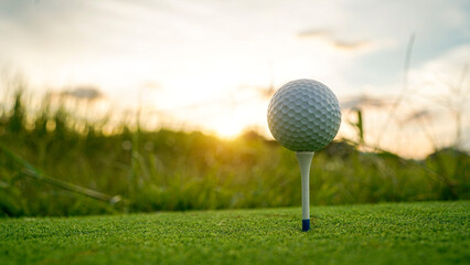Golf ball on green grass in the evening golf course with sunshine background.