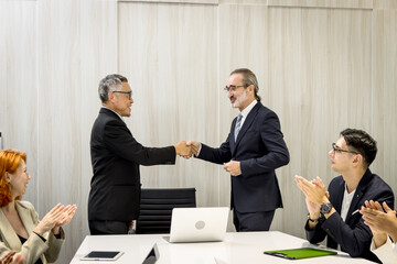 Group of diverse businesspeople at seminar conference, cheerful officers listen to presentation during meeting. Audiences clapping hands while businessmen having handshake after finish business deal.
